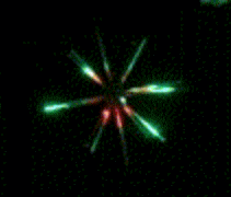 Green and red fireworks exploding in darkness.